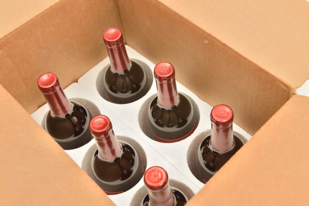 Six bottles of wine in a box being prepared for shipping after purchase online.